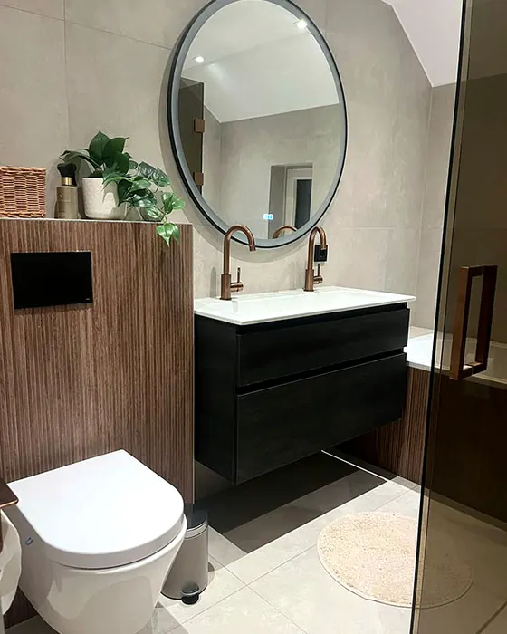 Toiletruimte met ronde spiegel, zwart wastafelmeubel en hangend toilet